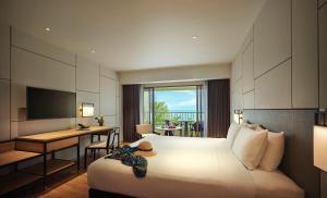 a hotel room with a bed and a desk and a television at PARKROYAL Penang Resort in Batu Ferringhi