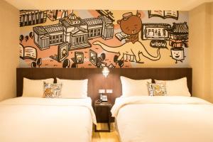 two beds in a hotel room with a mural on the wall at Just Live Inn-Taipei Station in Taipei