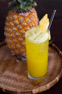 a glass of pineapple juice on a basket with a pineapple at Light House Hostel in Danang
