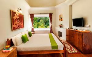 a bedroom with a bed with a window and a television at Teanest by Nature Resorts in Coonoor