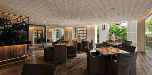 a restaurant with tables and chairs and a bar at PARKROYAL Penang Resort in Batu Ferringhi