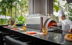 a chef preparing food in a restaurant kitchen at PARKROYAL Penang Resort in Batu Ferringhi