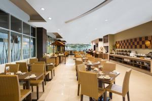 a dining room with tables and chairs and a cafeteria at Hotel Santika Bengkulu in Bengkulu