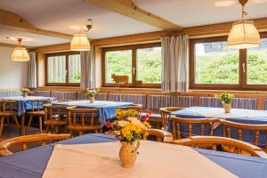 un restaurante con mesas y sillas azules y ventanas en Allgäu Ferienhaus Strobel, en Rosshaupten