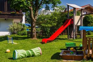 un parque infantil con un tobogán rojo en el césped en Allgäu Ferienhaus Strobel, en Rosshaupten