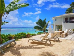 ein Haus mit Stühlen am Strand in der Nähe des Ozeans in der Unterkunft Ocean Spray Villas in Rarotonga