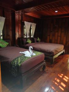 Un dormitorio con 2 camas y un cisne sobre un reposapiés en Heanmaeloung Resort., en Chiang Mai