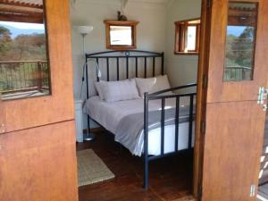 1 dormitorio con 1 cama en una habitación con ventanas en Gaia's Gift - Shepherd's Cottage, en Swellendam