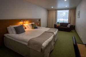 um quarto de hotel com uma cama grande e um sofá em Hotel Mesikämmen em Ahtari
