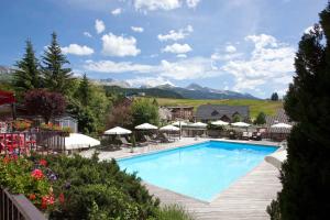 a large swimming pool with mountains in the background at Hotel Christiania in Villard-de-Lans