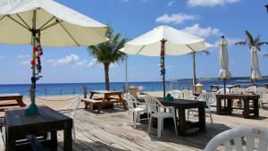 una terrazza in legno con tavoli e ombrelloni sulla spiaggia di 湛藍海岸民宿 Azure-零泊預約居-這個夏天有點藍--墾丁南灣沙灘-可包棟-國旅卡其他業別 a Nanwan