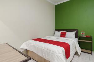a bedroom with a bed with a green wall at RedDoorz near Cikampek Mall Karawang in Karawang