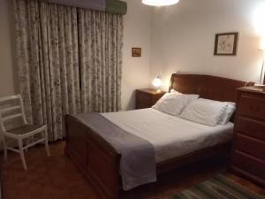 - une chambre avec un lit, une chaise et une fenêtre dans l'établissement Casa Sr do Calvário, à Paços de Ferreira