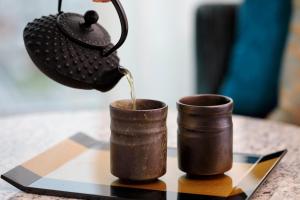 a tea kettle pouring tea into two coffee cups on a table at Osaka Marriott Miyako Hotel in Osaka