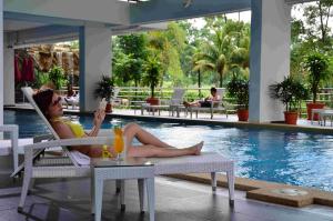 a woman sitting in a chair next to a swimming pool at Amansari Residence Resort in Johor Bahru