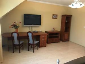 Cette chambre comprend un bureau avec une télévision et des chaises. dans l'établissement Lotusz Apartments in Nyiregyhaza, à Nyíregyháza