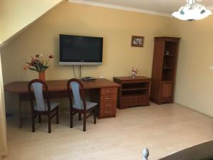 a room with a desk with a television and chairs at Lotusz Apartments in Nyiregyhaza in Nyíregyháza
