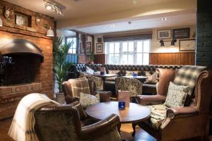 un bar avec des chaises et des tables en cuir ainsi qu'une cheminée dans l'établissement The Five Bells by Innkeeper's Collection, à Weston Turville