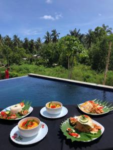 una mesa con tazones de comida en una mesa cerca de una piscina en Honeybee Homestay, en Kuta Lombok