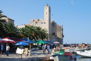 コミジャにあるApartments Picasso Komizaの時計塔を持って港を歩く人々