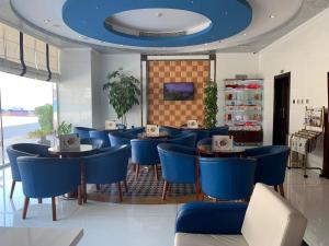 un restaurant avec des tables et des chaises bleues et un plafond bleu dans l'établissement Hala Inn Hotel Apartments - BAITHANS, à Ajman