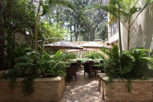 a patio with tables and chairs with plants and umbrellas at Reata Apartment Hotel in Nairobi