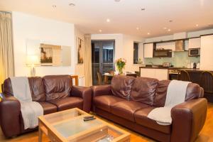 a living room with two leather couches and a kitchen at Spacous Dublin Escape 3BR Ensuited Free Parking in Dublin