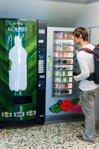 una mujer está buscando en una máquina expendedora de bebidas en Palace Hostel Vienna en Viena