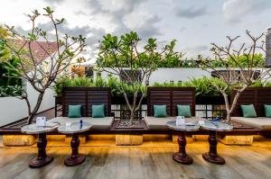 a patio with couches and tables and trees at The Aviary Hotel in Siem Reap