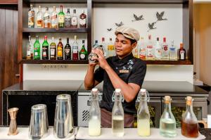 a man standing behind a bar making a drink at The Aviary Hotel in Siem Reap