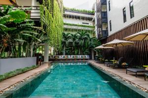 a pool in the middle of a building with plants at The Aviary Hotel in Siem Reap
