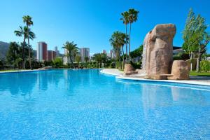 a large swimming pool with palm trees and buildings at Camping Villasol in Benidorm