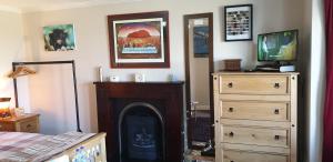 a bedroom with a fireplace and a bed and a dresser at Lighthouse Cottage (Shared Facilities) in Earlish