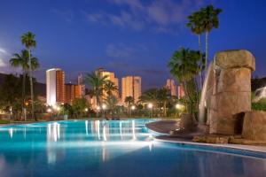 a large swimming pool with a city skyline at night at Camping Villasol in Benidorm