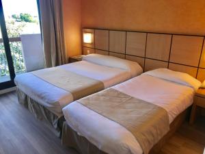 een hotelkamer met 2 bedden en een raam bij Chez Walter in Lucciana