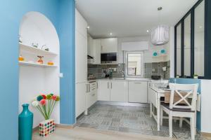 a kitchen with white cabinets and blue walls at Casa EVA Amêndoa in Tavira