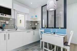 a kitchen with white cabinets and a table and chairs at Casa EVA Amêndoa in Tavira +2 photos