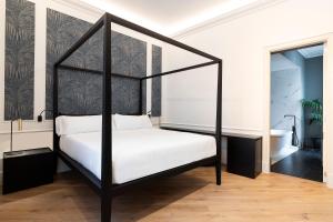 a black canopy bed in a room with a bathroom at Maldà Singular Hotel in Barcelona