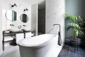a white bathroom with a tub and a plant at Maldà Singular Hotel in Barcelona