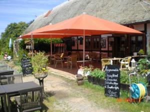 a restaurant with an umbrella and tables and chairs at Gaststaette & Pension Schinkenkrug in Hinrichshagen