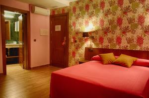 a bedroom with a red bedspread and a red wall at Le Petit León in León