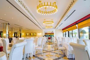 une salle à manger avec des chaises blanches et des lustres dans l'établissement Hotel Ariston, à Paestum