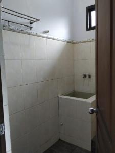a bathroom with white tiled walls and a window at Hotel "NGEBEL INDAH" in Ngebel