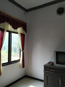 a living room with a tv and a window at Hotel "NGEBEL INDAH" in Ngebel
