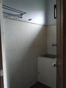 a bathroom with white tiled walls and a shower at Hotel "NGEBEL INDAH" in Ngebel