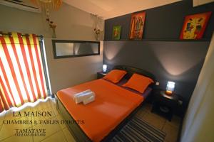 a small bedroom with an orange bed in it at La Maison in Toamasina