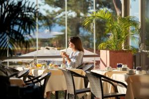 a woman sitting at a table in a restaurant at PortoBay Falesia in Albufeira