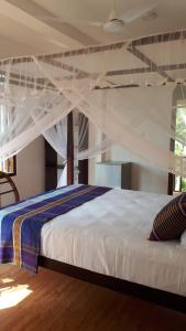 a bedroom with a bed with a white canopy at My Home Resort in Matara