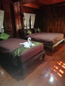 um quarto com duas camas e um cisne sentado numa cadeira em Heanmaeloung Resort. em Chiang Mai