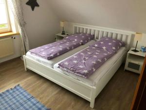 una cama con almohadas moradas en una habitación en Tolle Ferienwohnung in schönem Bauernhaus, en Fehmarn